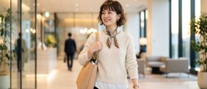 オフィスのロビーを後にする明るい表情の20代女性ビジネスパーソン